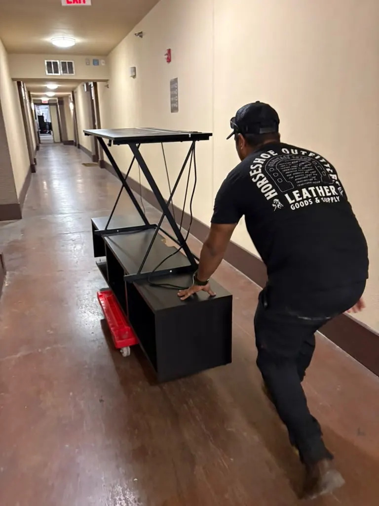 Crew member moving furniture down an apartment hallway
